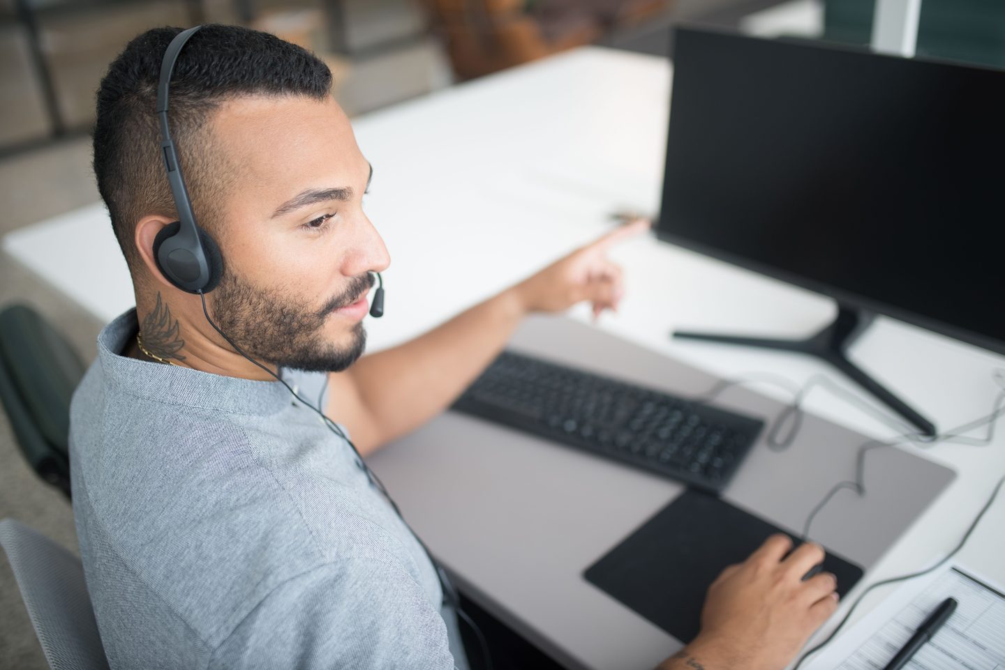 Bearded Man in Gray Shirt Wearing Bearded man in gray shirt wearing black headset using computer, representing UCSTAK's Agent Tools feature.