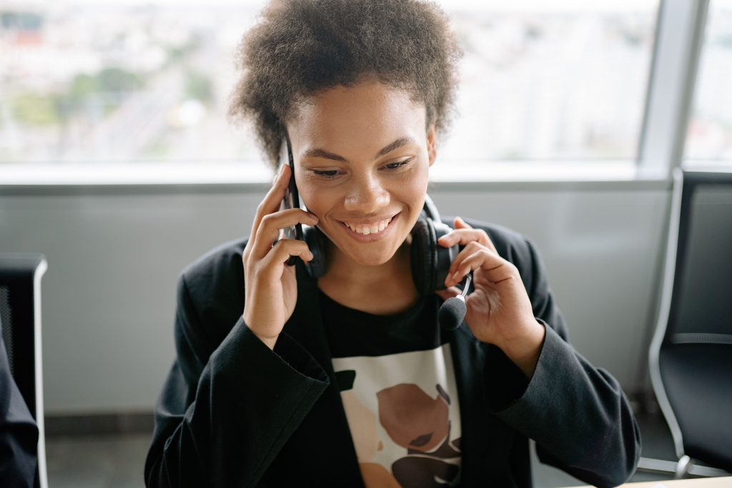 Woman with afro hair holding cellphone, representing UCSTAK's Outbound Dialer Suite feature.