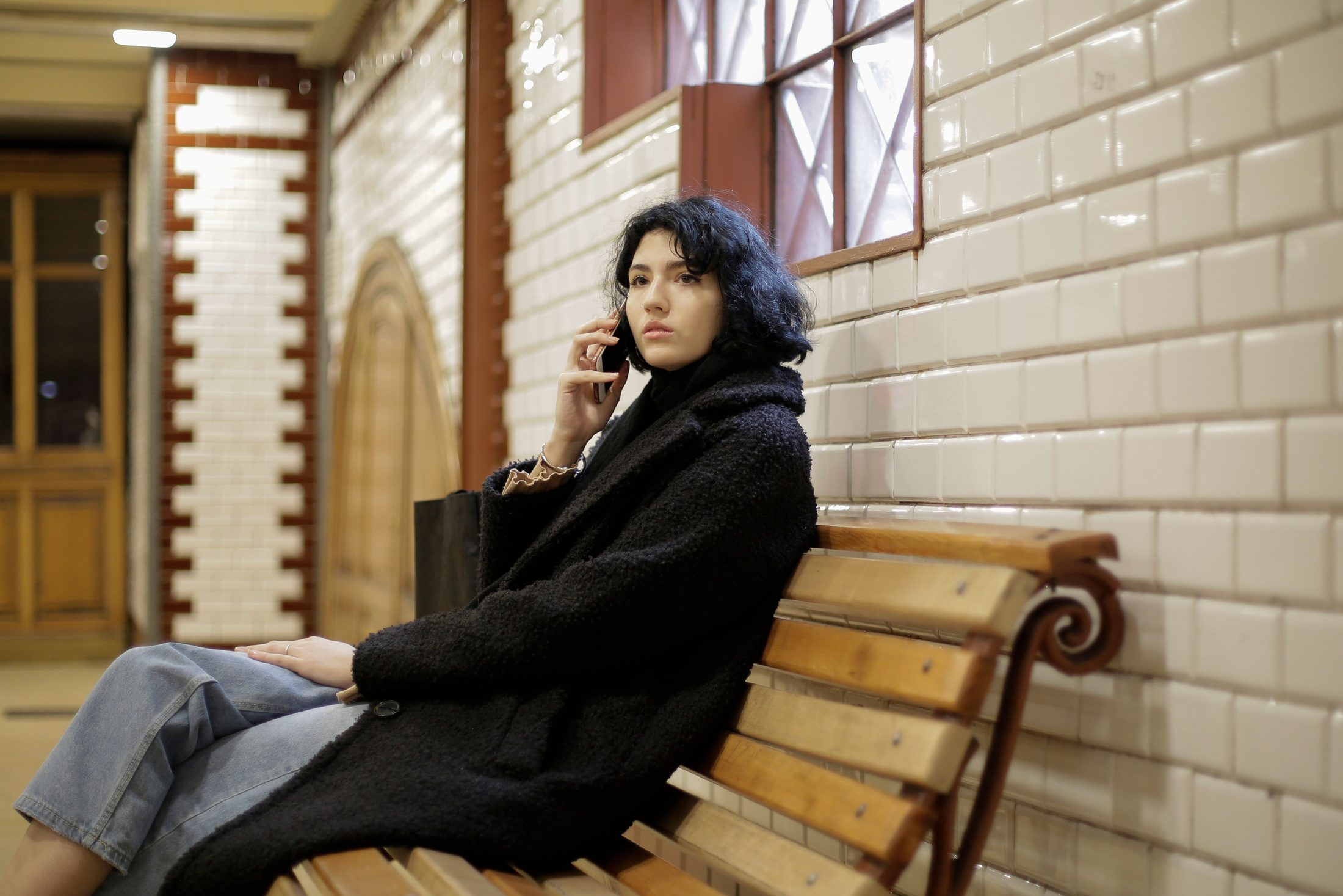Woman in Black Coat Sitting on Woman in black coat sitting on brown wooden bench, representing UCSTAK's Queue Position & Wait-Time Announcements feature.