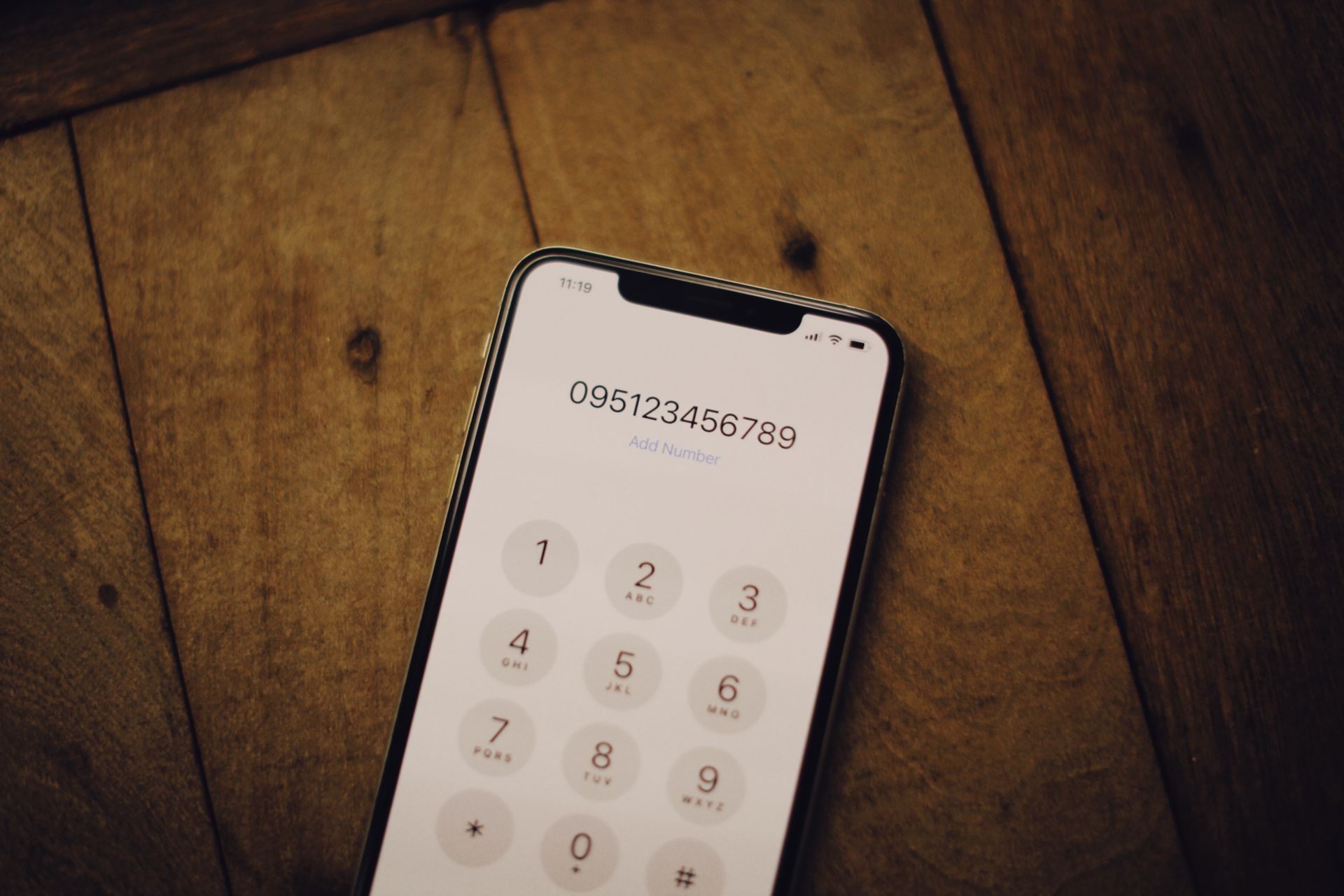 Close Up Shot of a Mobile Close up shot of a mobile phone on wooden surface, representing UCSTAK's Routing a Published Number Straight to a Menu feature.