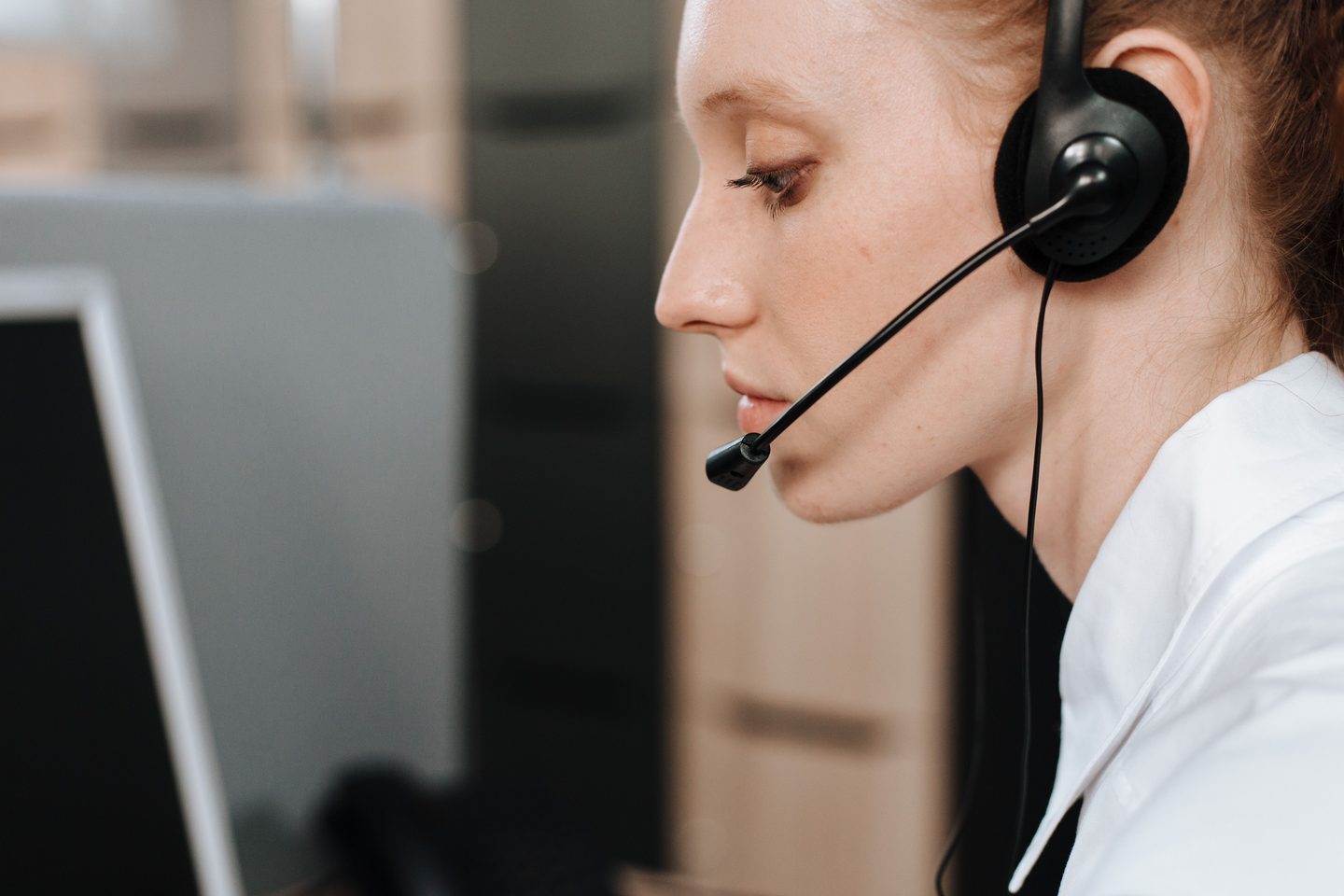 Side View of a Woman Wearing Side view of a woman wearing headset, representing UCSTAK's Emergency Calling (E911) feature.