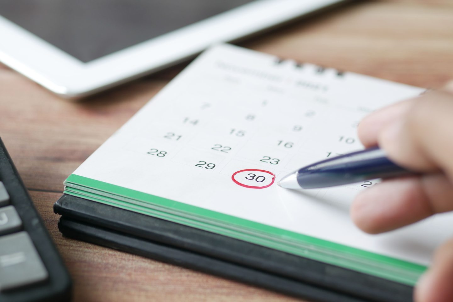 A person holding black pen pointing on calendar, representing UCSTAK's Number Porting feature.