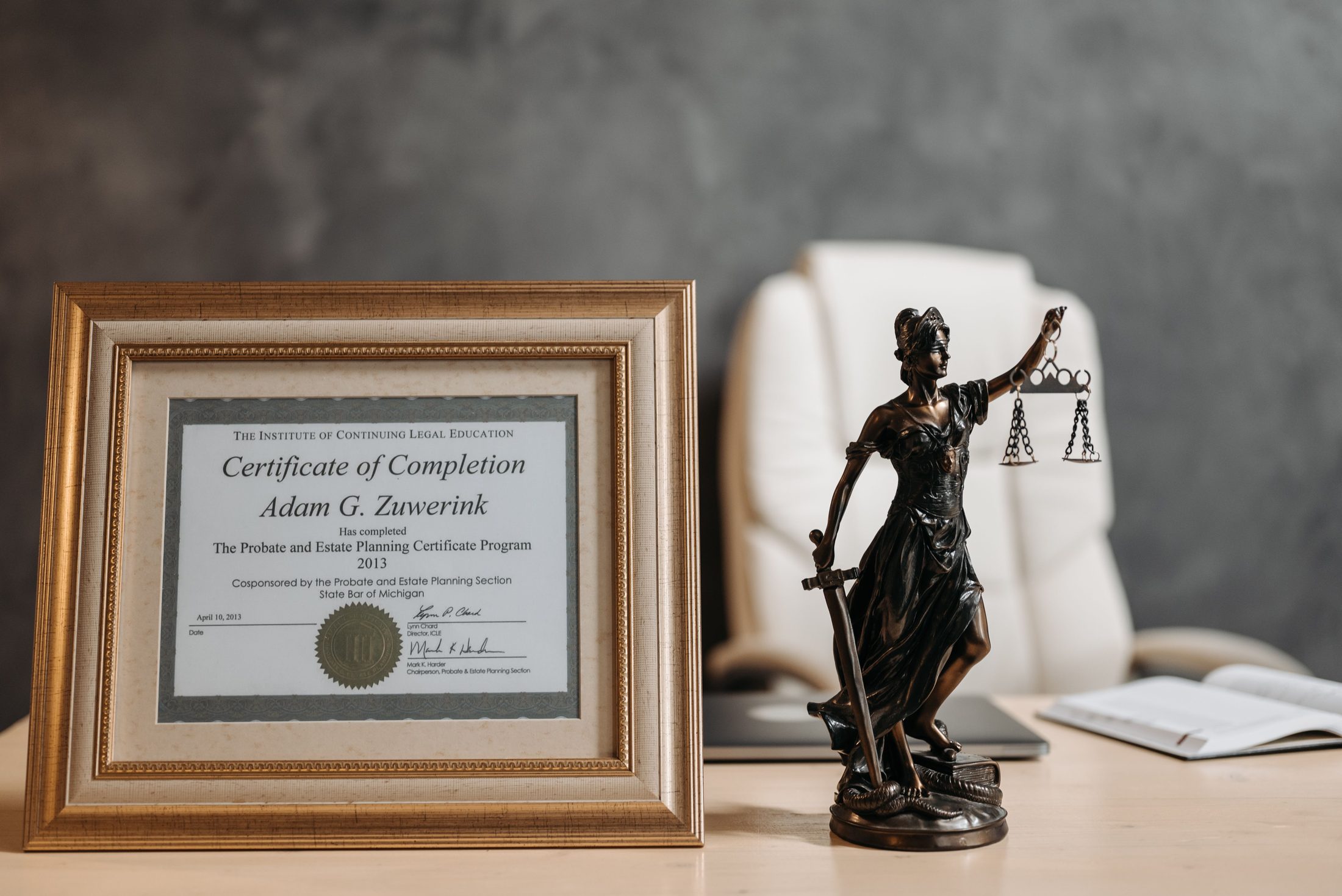 A certificate and lady justice figurine on table, representing UCSTAK's Compliance feature.