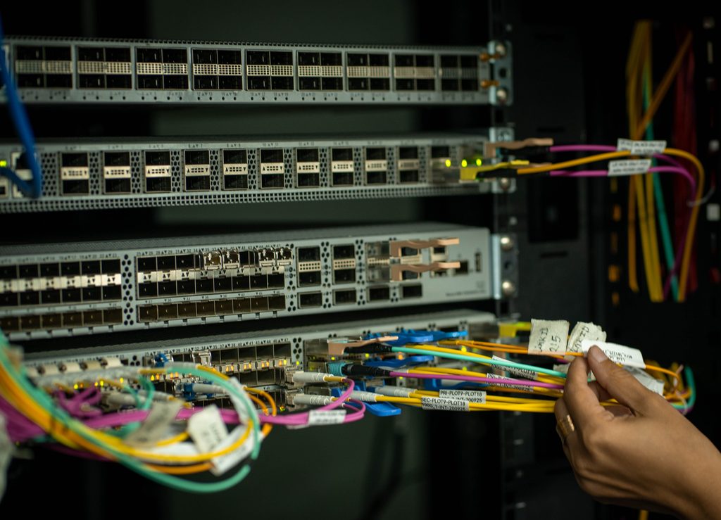 Hands working on network cables in data center, representing UCSTAK's Network Management feature.
