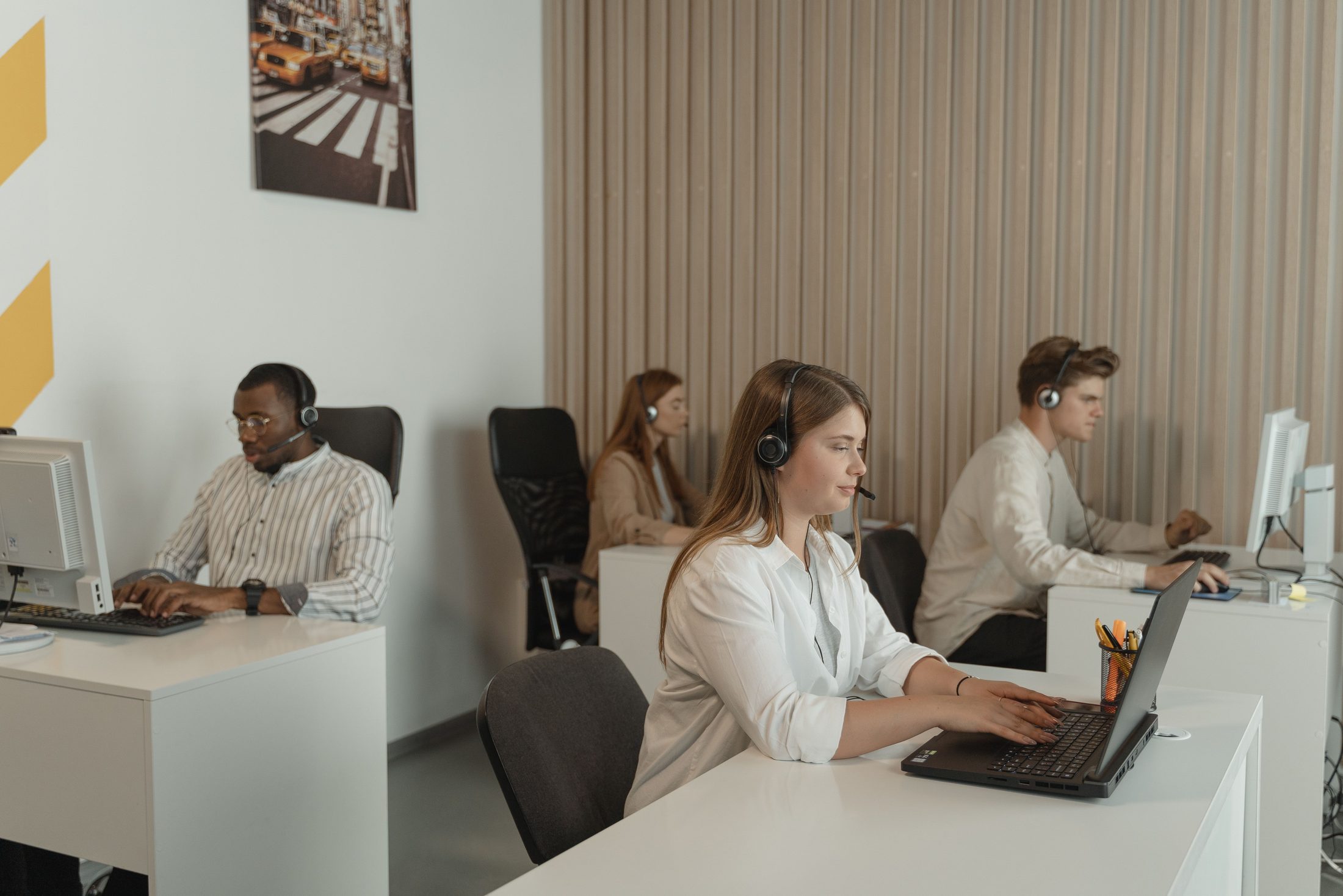 Four People Working in Call Center Four people working in call center office, representing UCSTAK's 24/7 Infrastructure Monitoring feature.