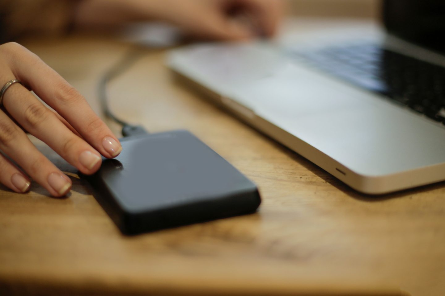 Black square device on brown wooden table, representing UCSTAK's Automatic Backups feature.