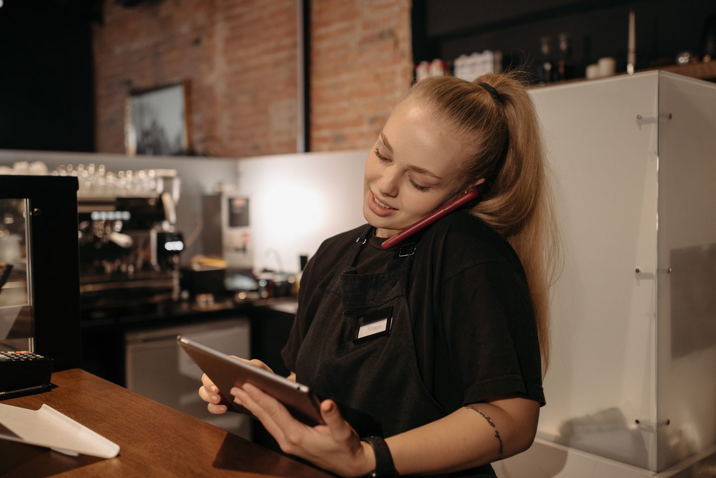 Woman in black crew neck shirt taking online order using smartphone on UCSTAK's Retail page.
