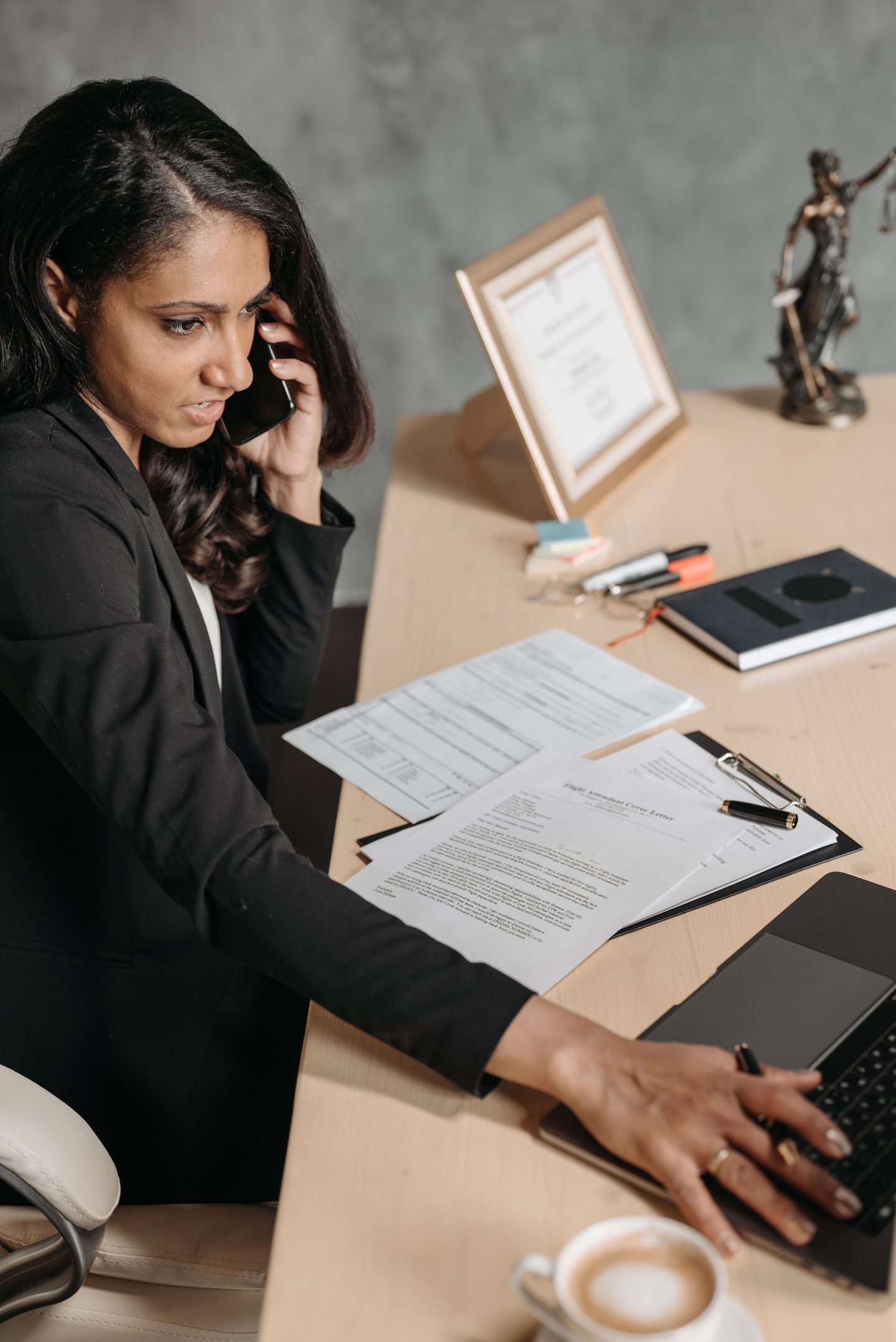 Woman in suit talking on phone and working on laptop on UCSTAK's Legal page.